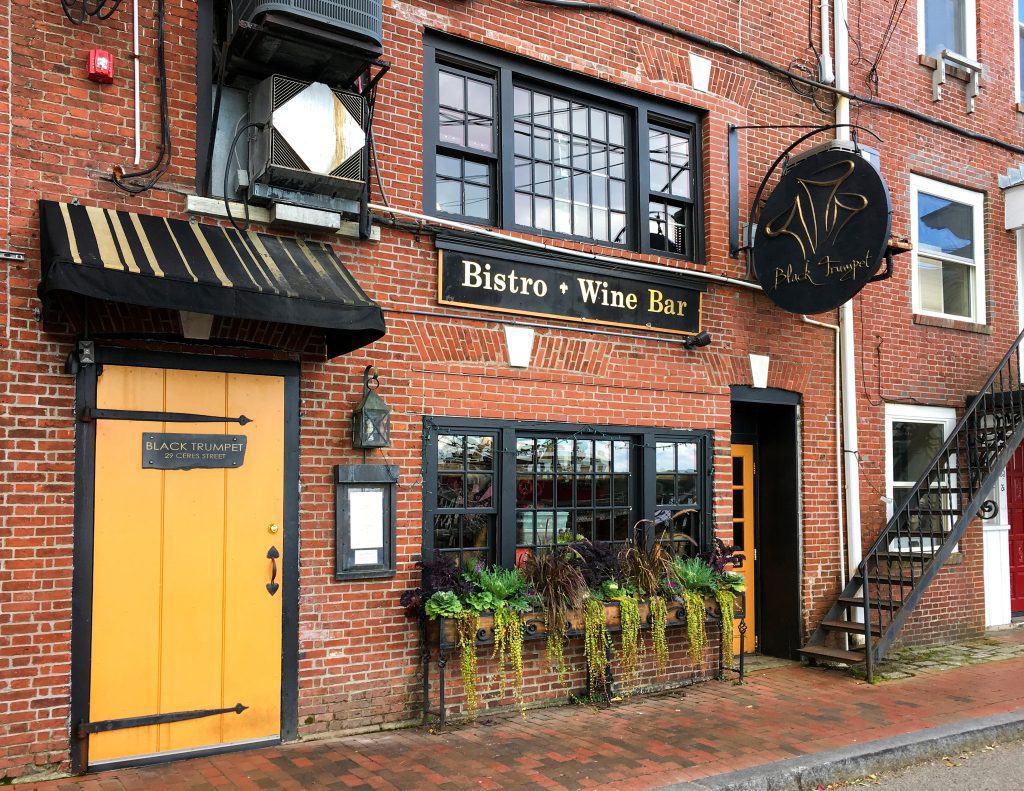 The Black Trumpet restaurant: a red brick building with a yellow door and the words Bistro, Wine Bar on a sign.