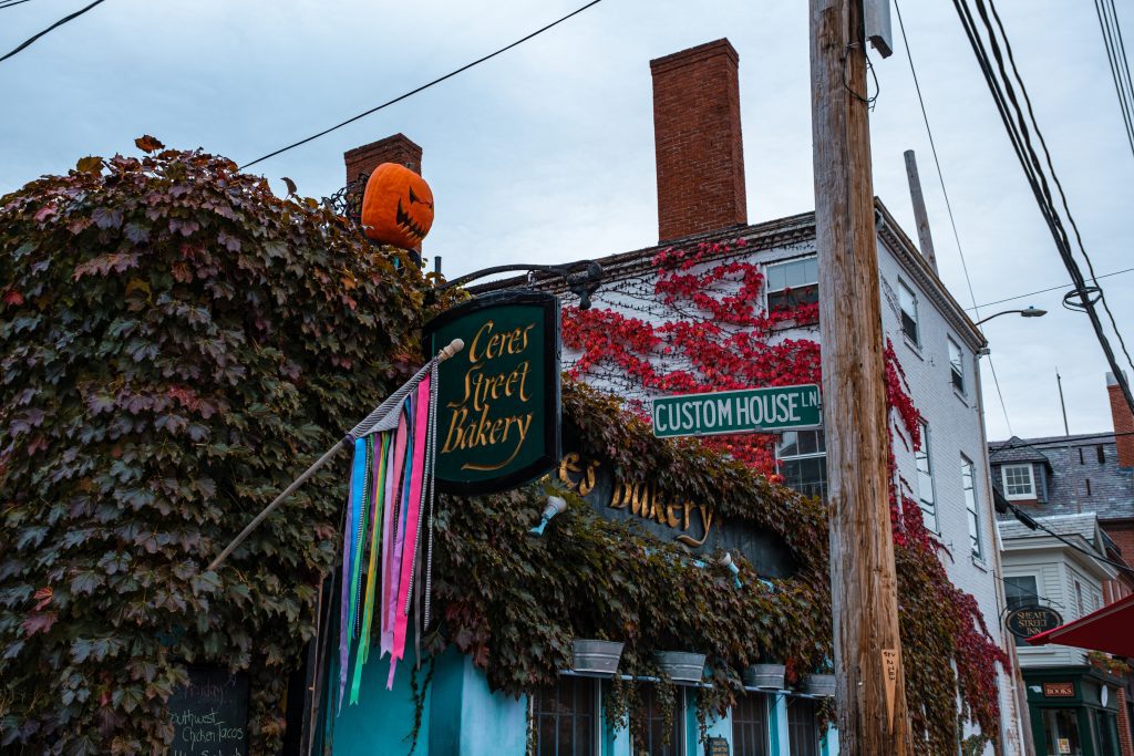 An ivy-covered building with a sign reading Ceres Street Bakery and a flag of rainbow-colored ribbons.