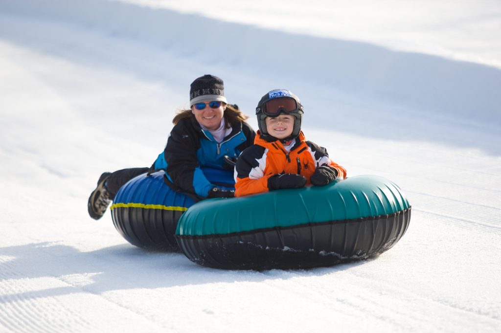 A mom and son snow tubing together.