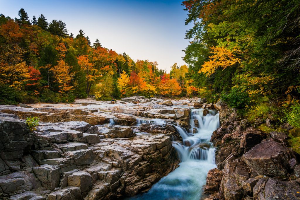 A flowing waterfall in Rocky Gorge, surrounded by orange and green trees in the fall.