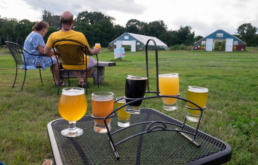 A sampler of four beers on a table on the grass at the farm of Throwback Brewery.