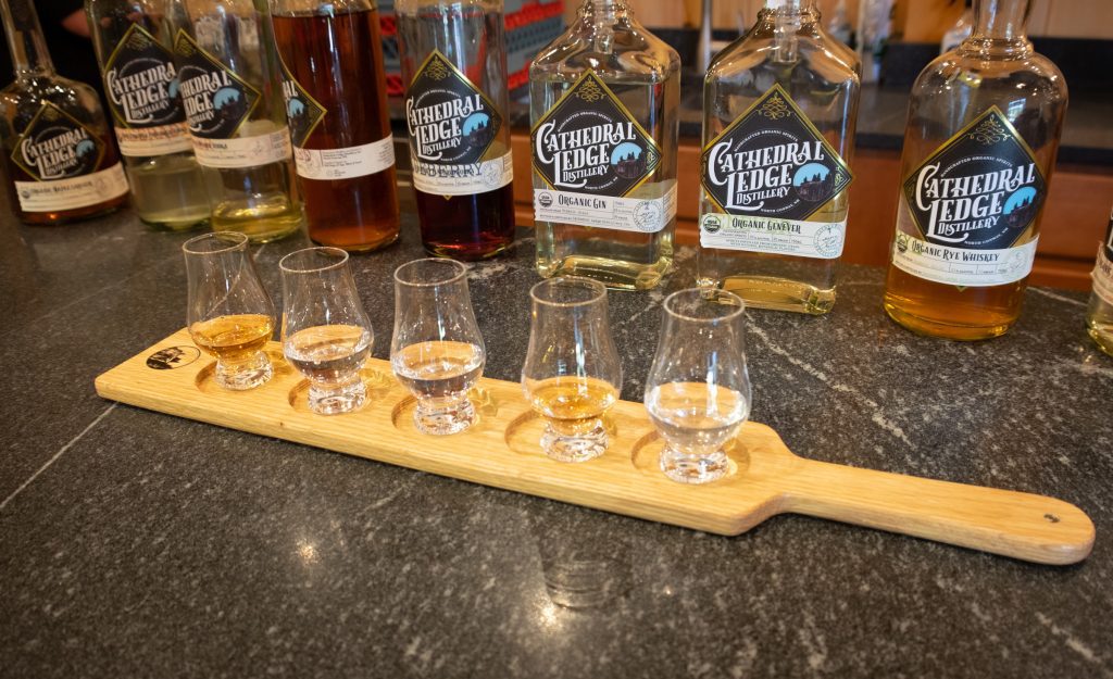 A paddle with five samples of spirits in front of their bottles at Cathedral Ledge Distillery.
