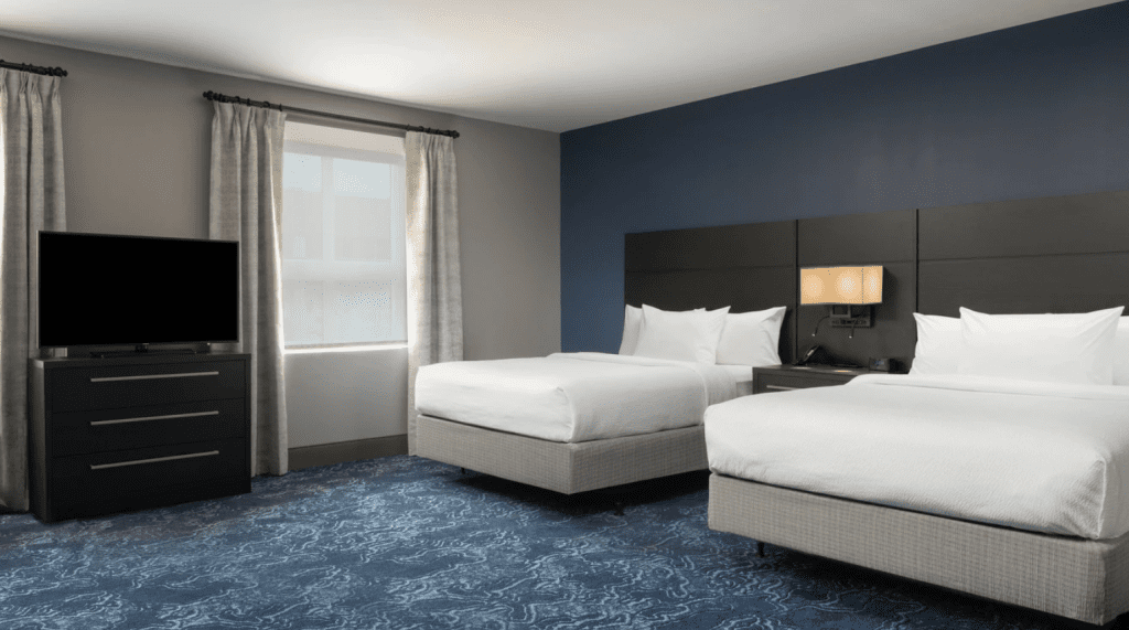 A hotel room with two queen beds and blue walls and floor