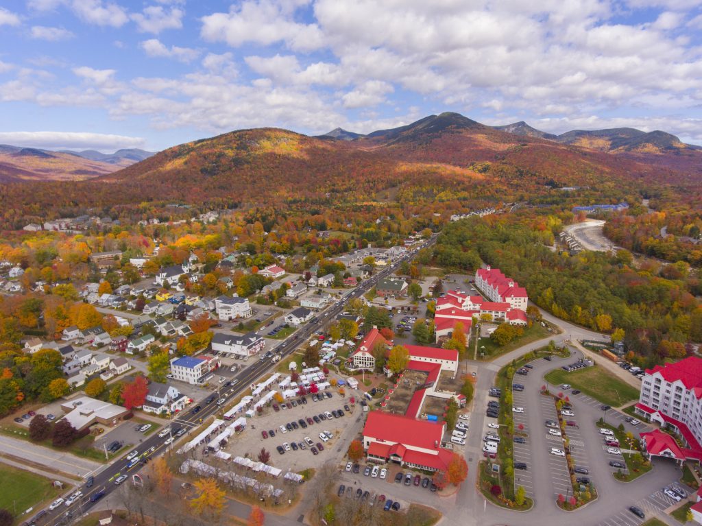 An aerial view over the red buildings of Lincoln, NH, mountains in the distance.