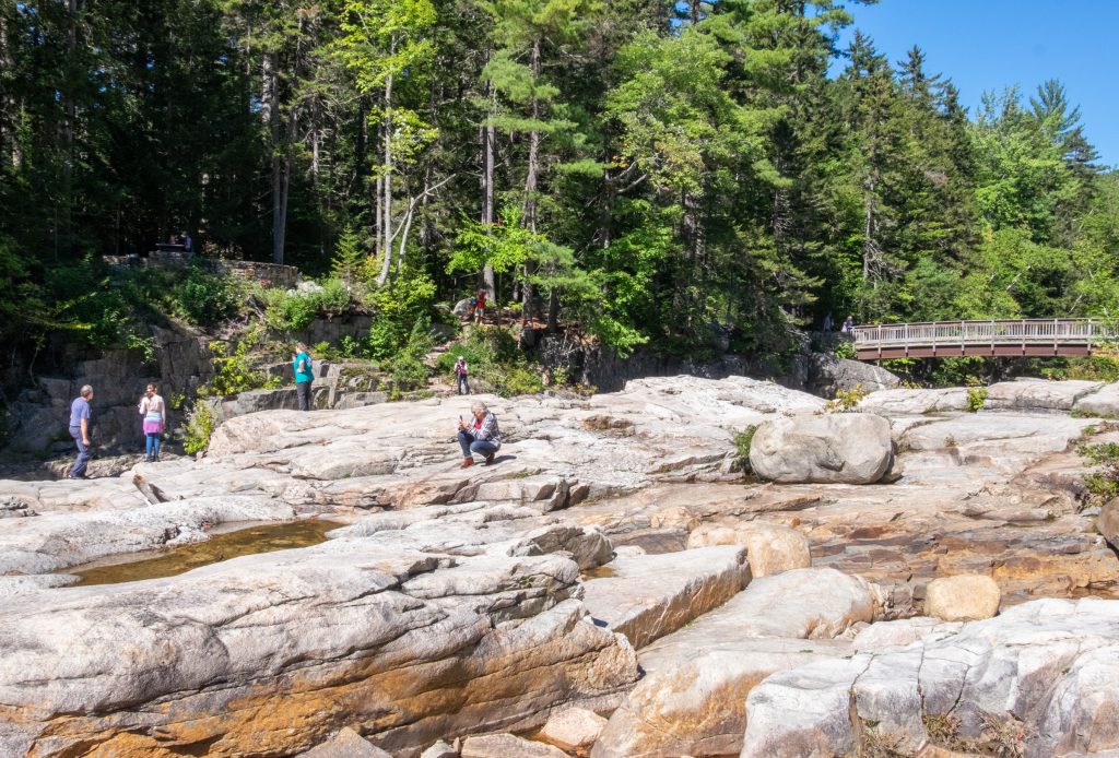 A flat rocky expanse area, several people walking on the rocks and taking photos.