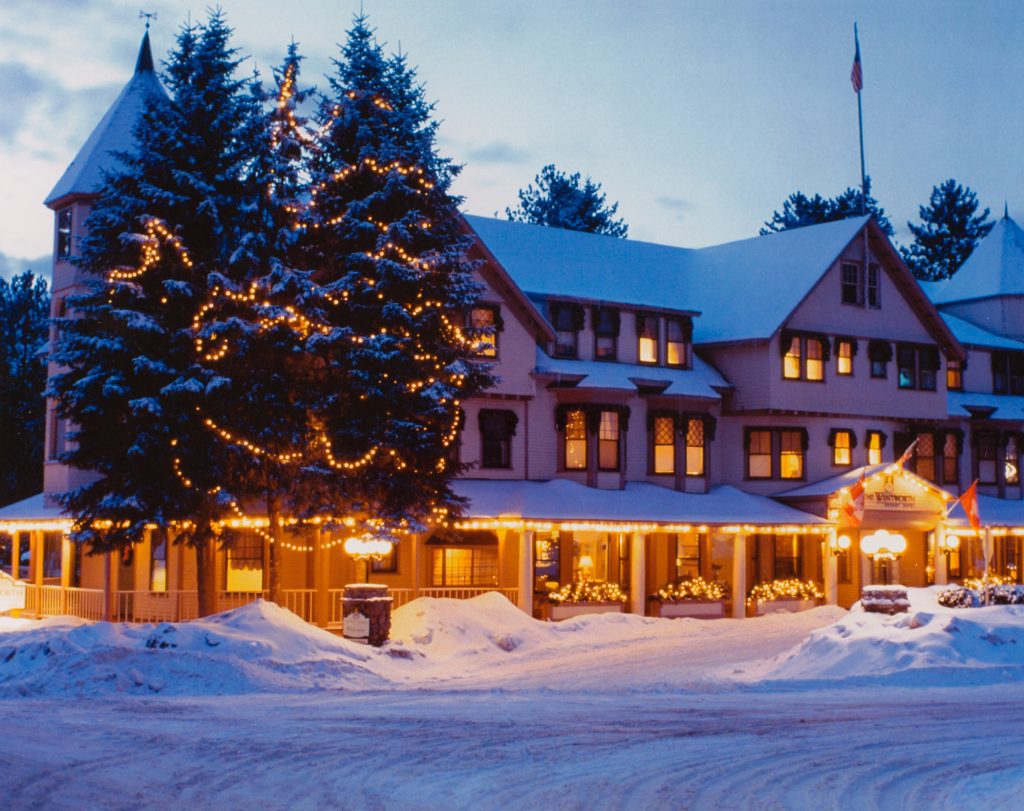 The Wentworth inn surrounded by deep snow and evergreen trees topped with Christmas lights.