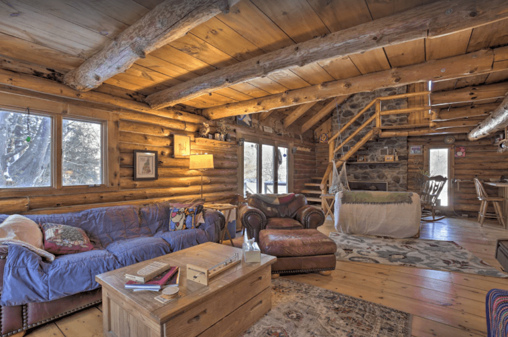 The living room of a log cabin with a couch and coffee table
