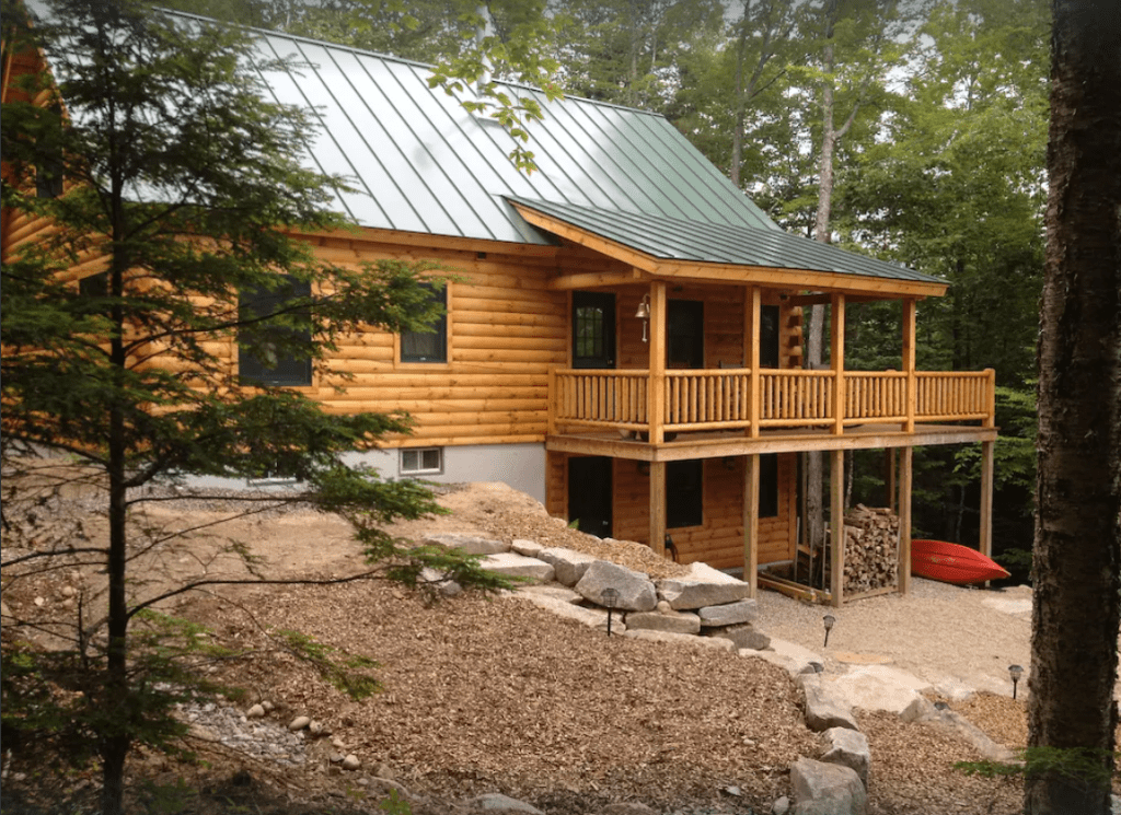 A two story log home with a wrap around porch on the second level