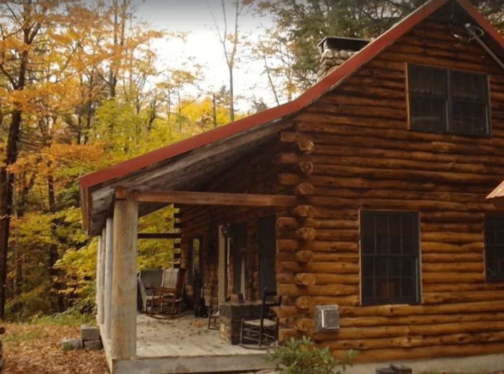 Side view of a log cabin with rocking chairs on the front