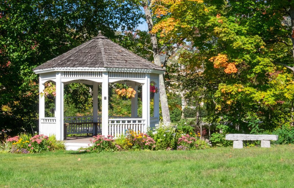 A white gazebo decorated with flowers on a lawn.