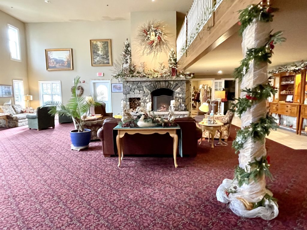 A cozy front room in an inn decorated for Christmas, with couch in front of a big fireplace.
