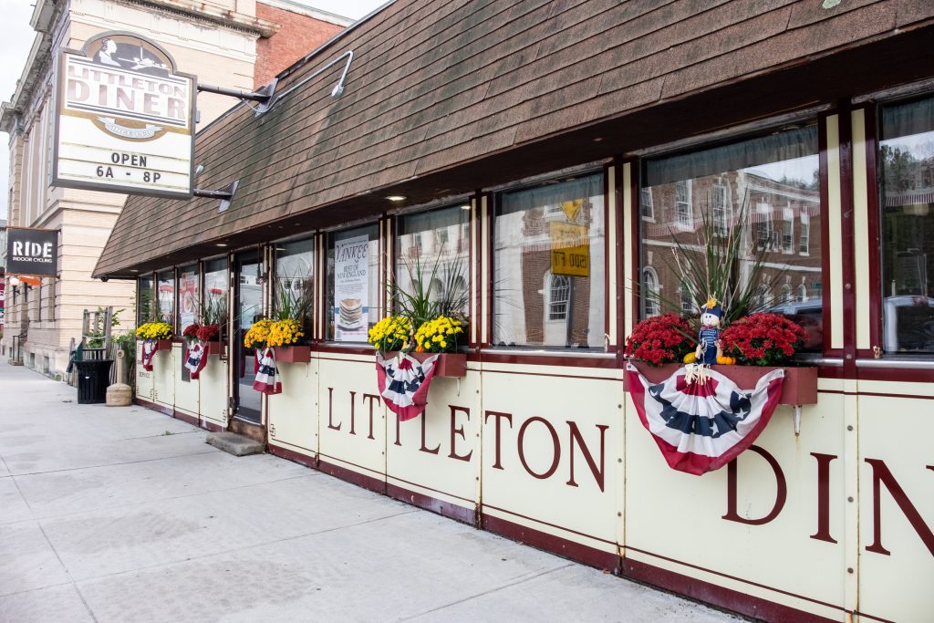 The outside of an old-fashioned vintage diner with signs reading Littleton Diner.
