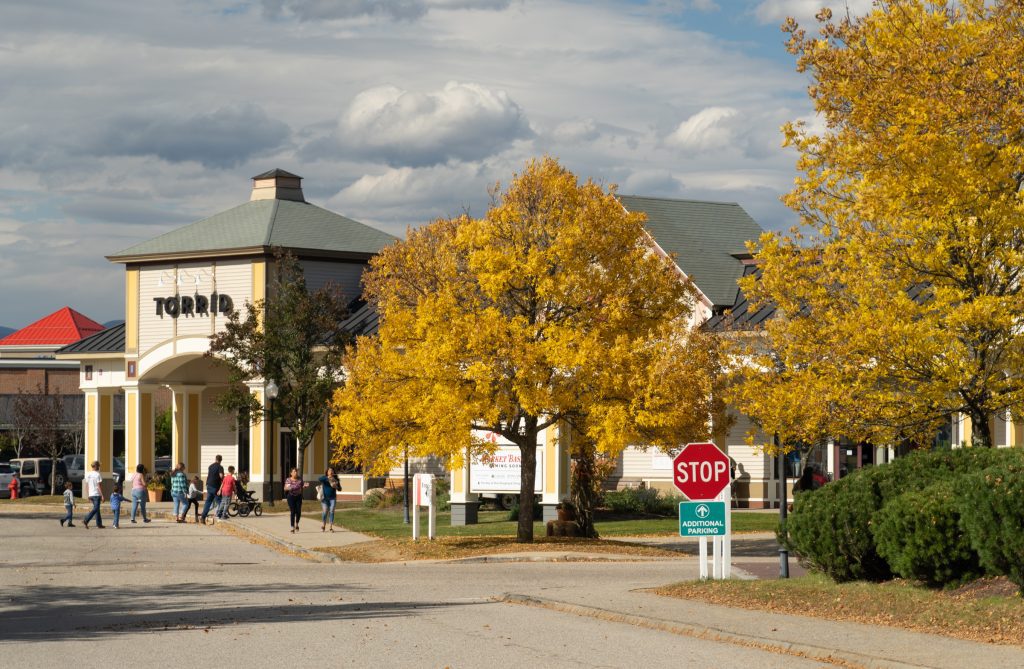 An outdoor shopping mall with lots of bright yellow trees in fall.