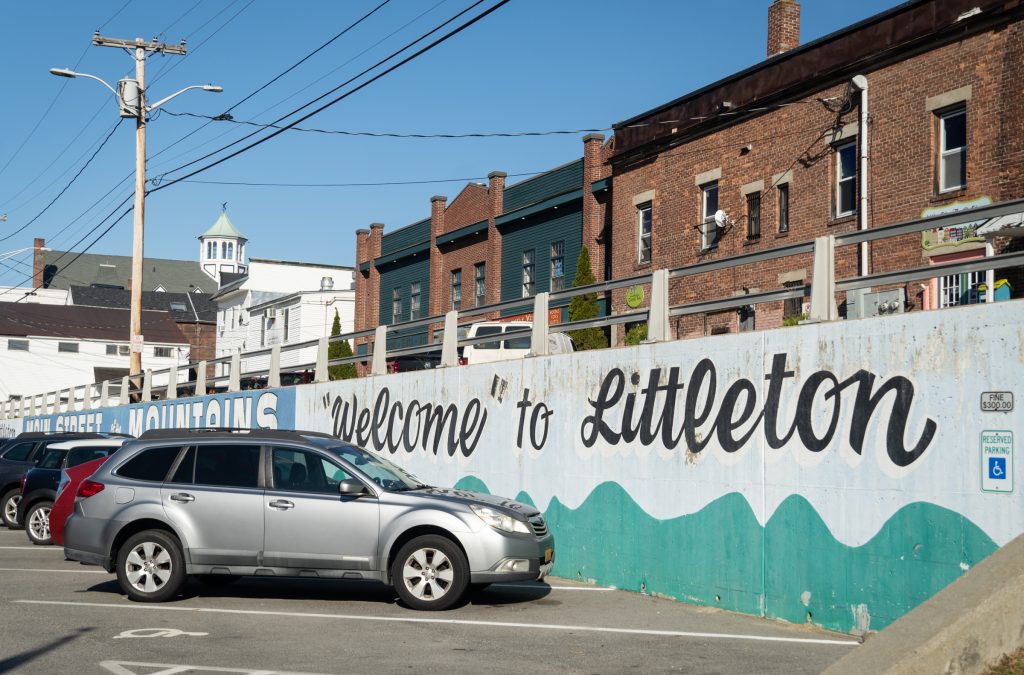 A car parked in front of a mural reading Welcome to Littleton.