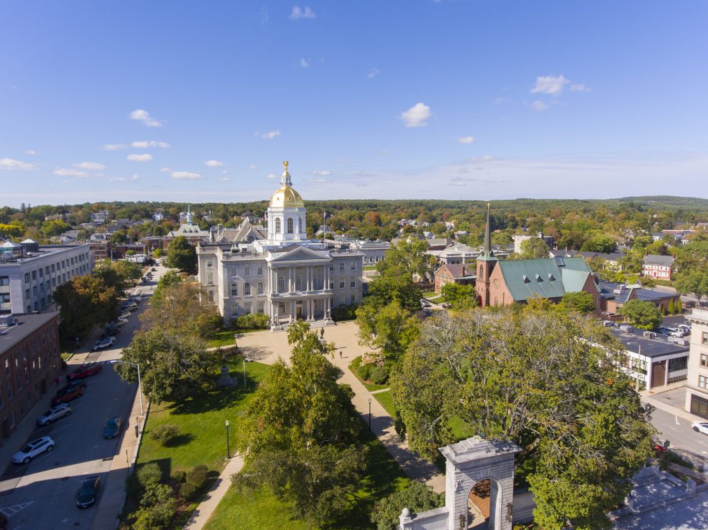 A skyline view of Concord's granite state house with a gold dome overlooking a big park.