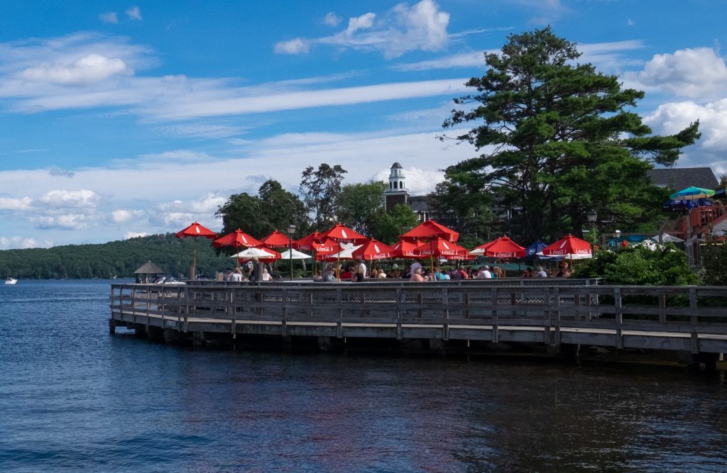 A restaurant on a dock on the lake, tables covered with bright red umbrellas.